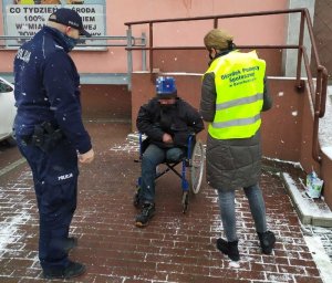 Policjant i pracownik OPS rozmawiają z niepełnosprawnym mężczyzną